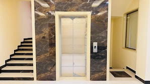 A modern elevator with a marble wall, a staircase on the left, and a plain wall on the right. - Kreston Heights Hotels Bhopal (Bhopal)