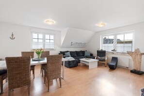 Ein modernes Wohnzimmer mit Essbereich, einer Sofagarnitur und einem großen Fenster.