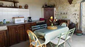 A rustic kitchen with wooden cabinets, a microwave, and a dining table set with chairs. - Renaissance Room – Provençal Charm and Serenity (Théziers)