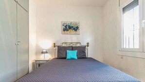 Une chambre à coucher avec un lit, une table de chevet, une lampe, un tableau au mur et une fenêtre.