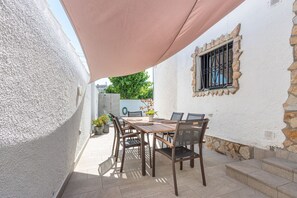 Eine Terrasse mit Tisch und Stühlen, einem Blumentopf und einer Steinmauer.