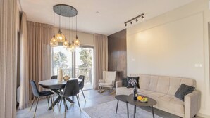 A modern living room with a dining area, a sofa, and a chandelier. - 1 BR Apartment in Ha-Neviim (w/ safe room) (Jerusalem)