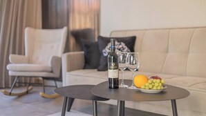 A modern living room with a sofa, a small round table with a bottle and glasses, and a bowl of fruit. - 1 BR Apartment in Ha-Neviim (w/ safe room) (Jerusalem)