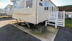 A mobile home with a porch, a small deck, and a window with a view. - The Beachside Hideout - St Michaels Caravan Park (Abergele)