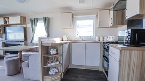 A compact kitchen with a microwave, stove, and cabinets. - The Beachside Hideout - St Michaels Caravan Park (Abergele)