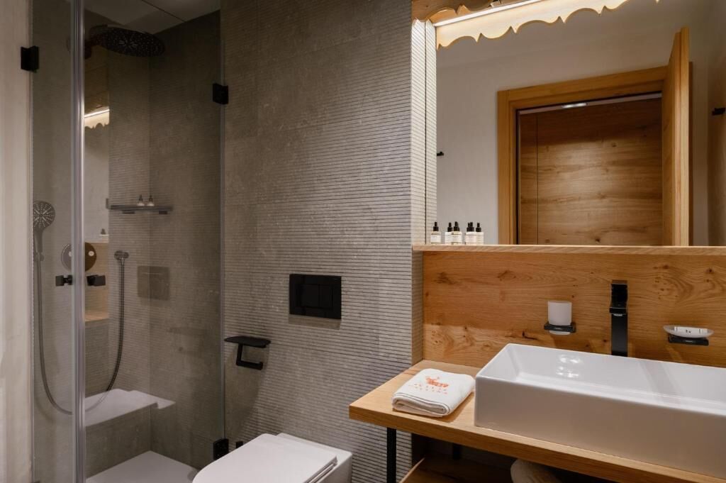 A modern bathroom with a glass-enclosed shower, a wooden vanity with a sink, and a mirror.