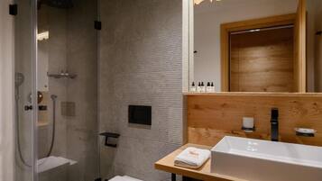 A modern bathroom with a glass-enclosed shower, a wooden vanity with a sink, and a mirror.
