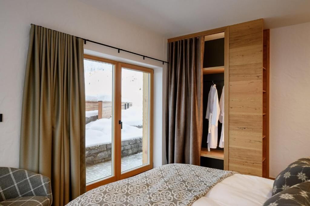 Ein Schlafzimmer mit einem Bett, einem Holzschrank und einer Glastür zu einem verschneiten Außenbereich.