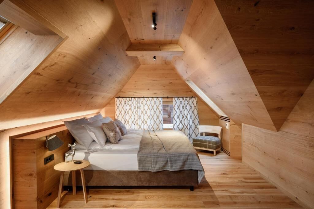 Un dormitorio acogedor en el ático con una cama, una mesita y una silla.