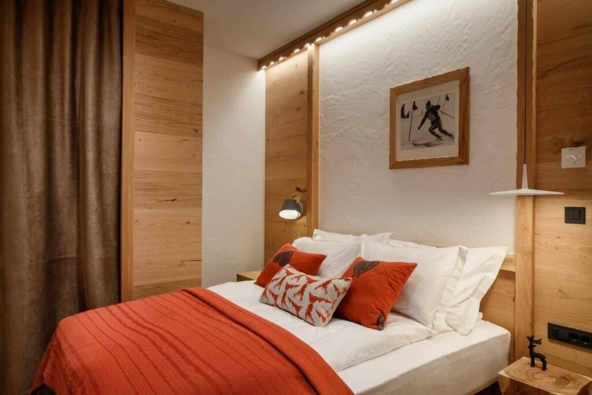 A bedroom with a bed, pillows, a nightstand, a lamp, and a framed picture on the wall.
