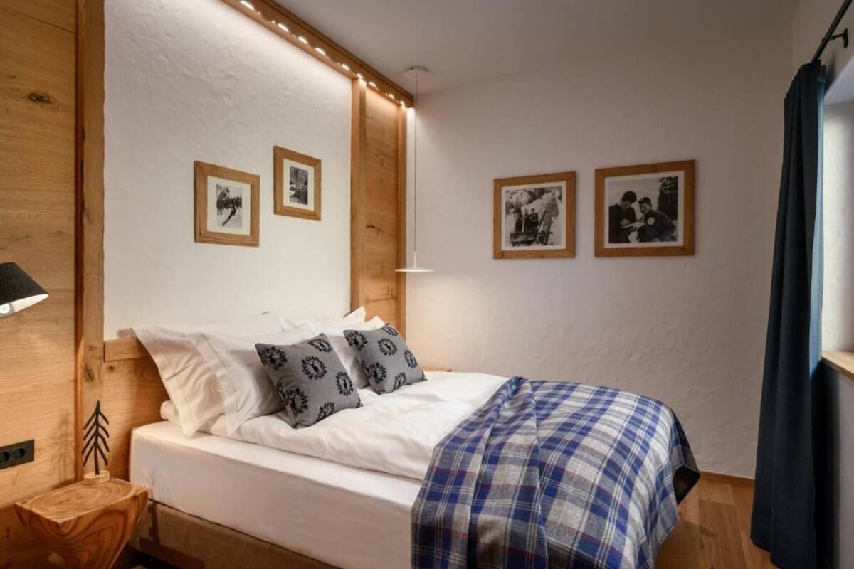 A bedroom with a bed, wooden headboard, bedside table, and wall-mounted pictures.