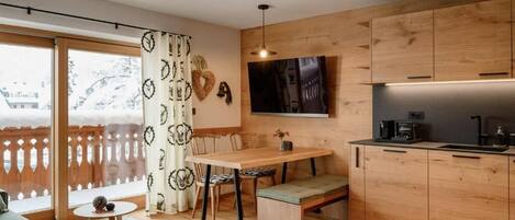 A modern kitchen with wooden cabinets, a dining table, and a built-in bench.