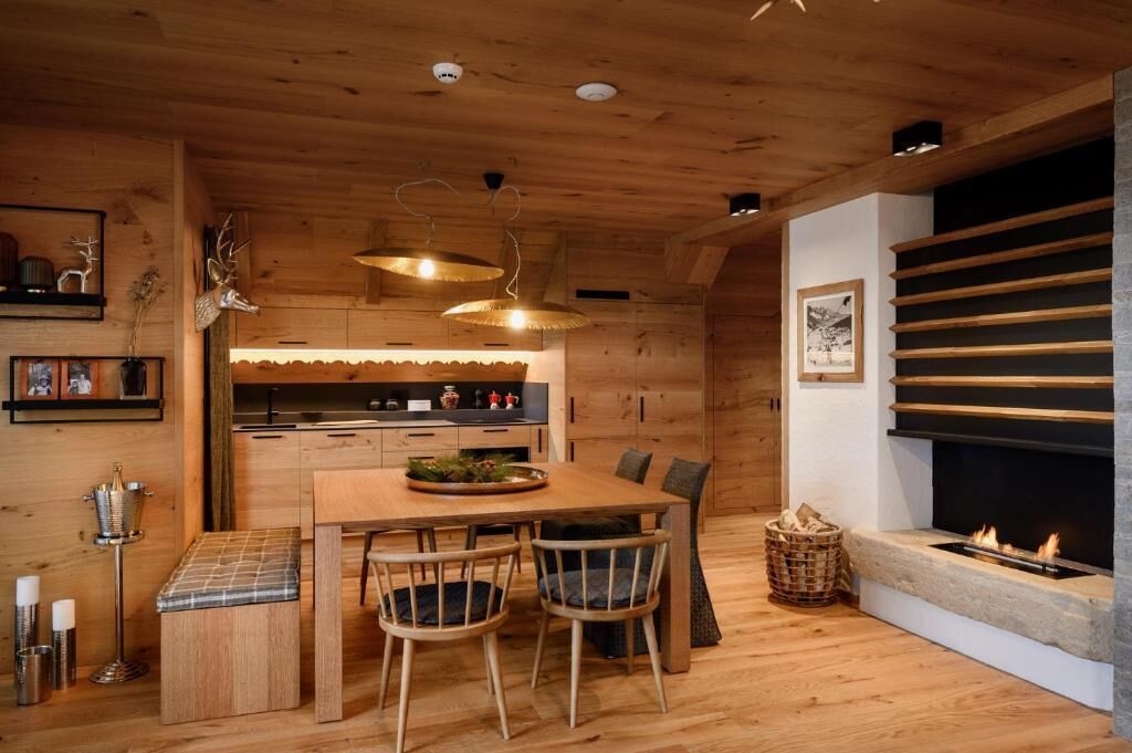 A wooden interior with a dining area, a fireplace, and a kitchen.
