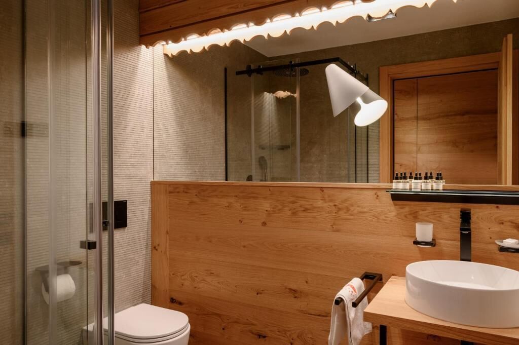 Ein modernes Badezimmer mit einer Duschkabine aus Glas, einem Holzbadezimmer-Möbel und einem großen Spiegel.