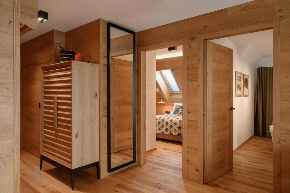 A room with wooden walls, a mirrored wardrobe, a skylight, and a bed with a patterned bedspread.