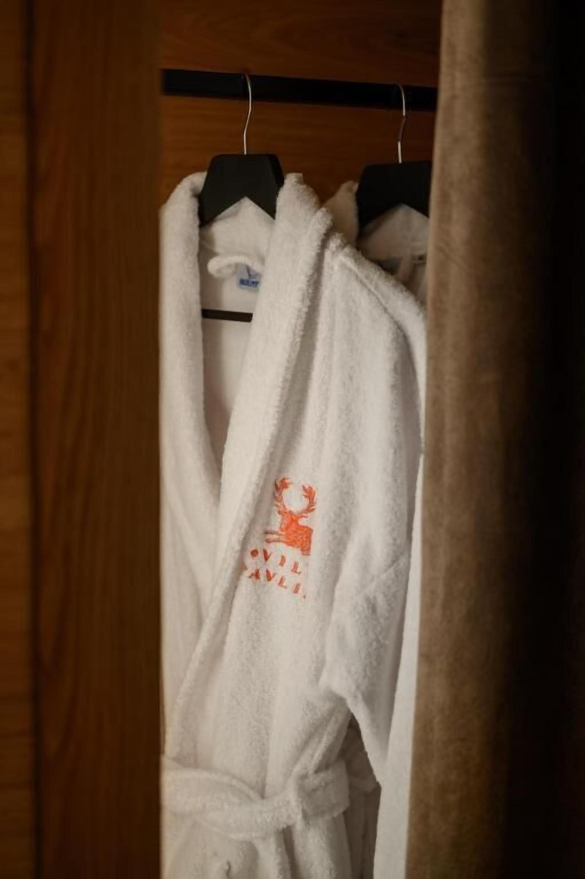 A white robe with a reindeer design hanging on a black hanger.