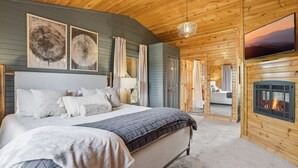 Un dormitorio acogedor con una cama grande, una chimenea y un televisor.
