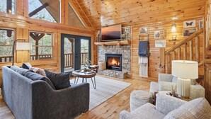 Interior acogedor de una cabaña con chimenea, paredes de madera y una zona de estar confortable.