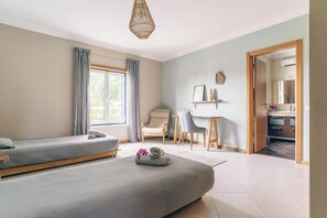 A bedroom with two beds, a desk, a chair, and a bathroom visible through an open door. - Beautiful Two-Storey Surf Villa Near Arrifana & Monte Clérigo (Aljezur)