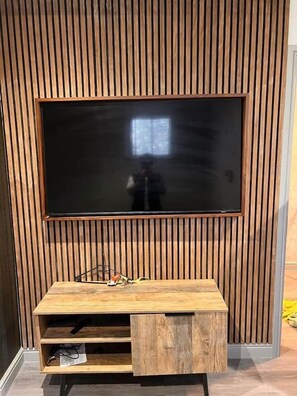 Ein Flachbildfernseher an einer Holzwand, darunter ein Holz-Entertainment-Möbel.