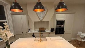 Cocina moderna con una isla grande, iluminación colgante y armarios blancos.