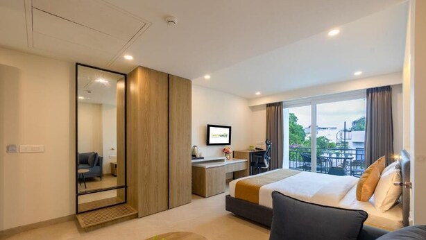 A modern hotel room with a bed, a desk, a sofa, and a balcony with a view. - Limewood Signature-Golf Course Extension (Gurugram)