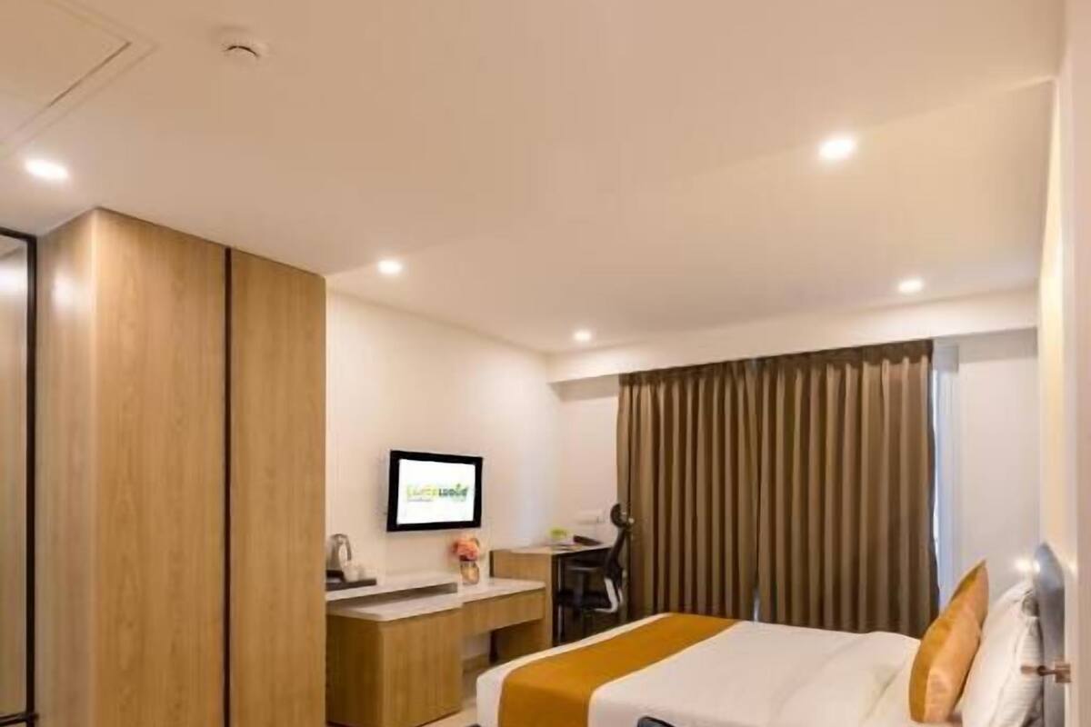 Una habitación de hotel moderna con cama, escritorio, televisor y sofá.
