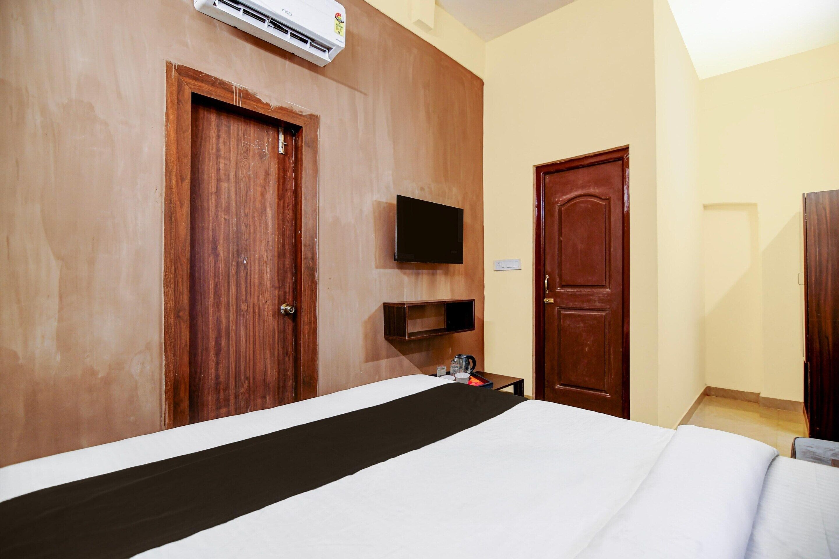 A hotel room with a bed, a television mounted on the wall, and a wooden door.