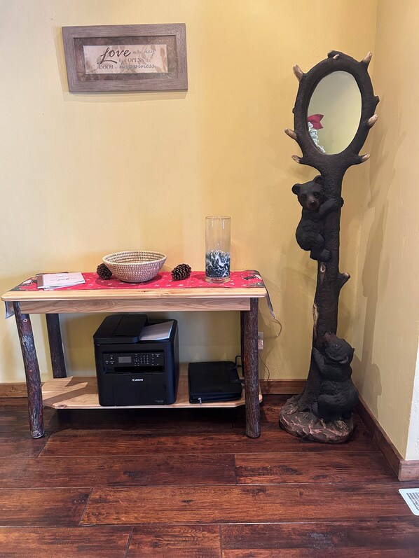 A desk with a printer, a basket, a glass vase, and a mirror with a bear design. - Charming family friendly house in Historic Somerset with lots to do (Somerset)