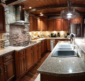 A kitchen with wooden cabinets, a granite countertop, a stove, and a sink. - Charming family friendly house in Historic Somerset with lots to do (Somerset)