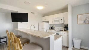 A modern kitchen with white cabinets, a marble countertop, and a built-in TV. - Penthouse 2BR, Wi-Fi, SMART TVs, Amazing Views! (Myrtle Beach)