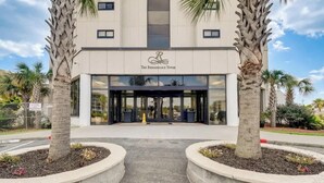 The Renaissance Tower with a modern facade, large glass entrance, and palm trees in the foreground. - Penthouse 2BR, Wi-Fi, SMART TVs, Amazing Views! (Myrtle Beach)