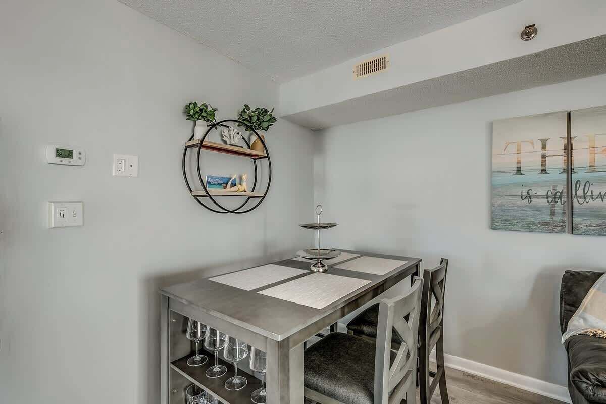 A modern dining area with a table, chairs, and a wine rack.