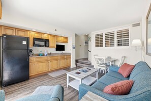 Un espacio habitable compacto con kitchenette, un sofá, una mesa de centro y una zona de comedor.