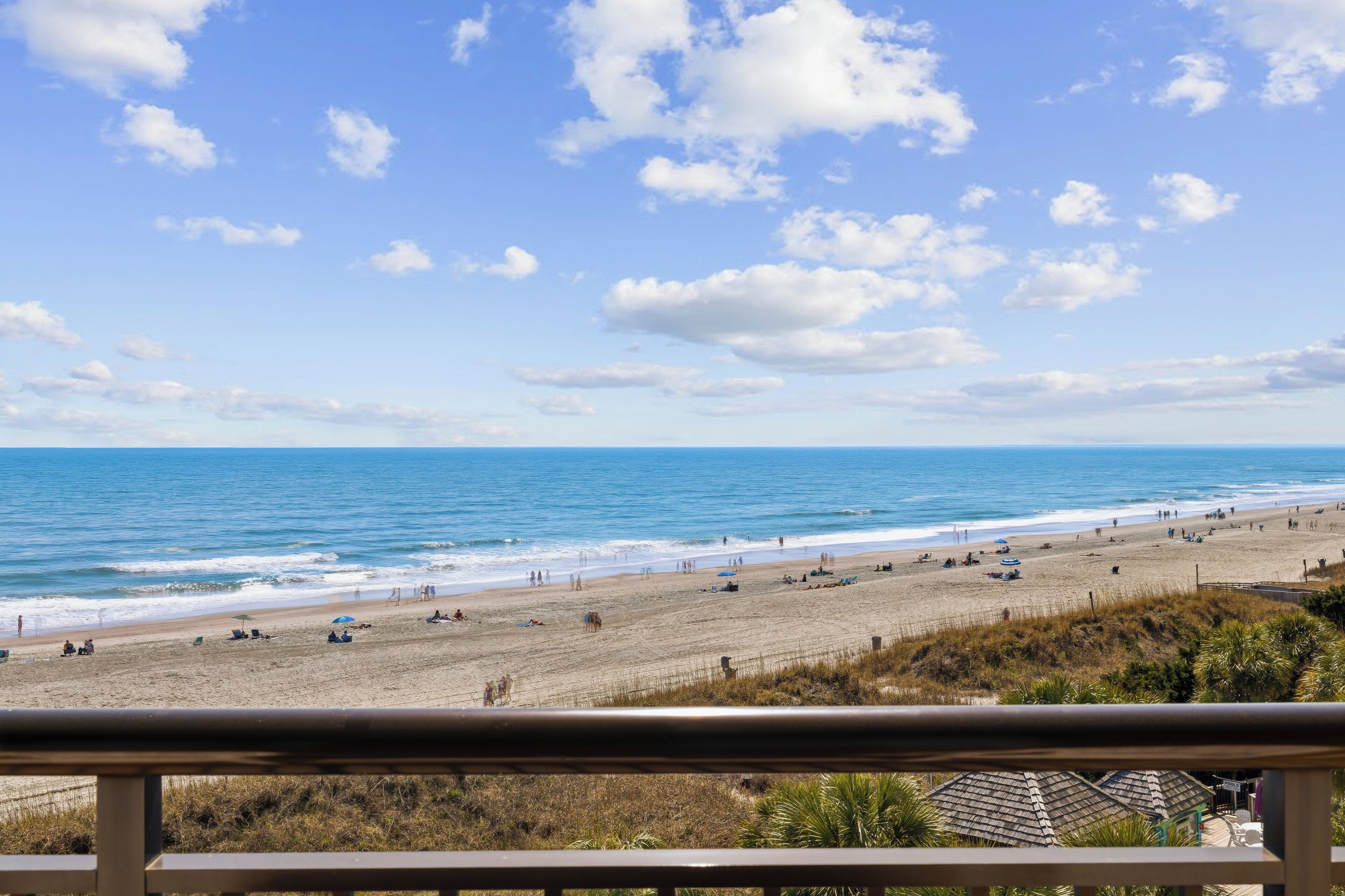 A beach with a clear sky, a sandy shore, and a few umbrellas.