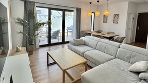 Ett modernt vardagsrum med en grå soffa, ett träbord som används som soffbord och en matplats med ett bord och stolar.