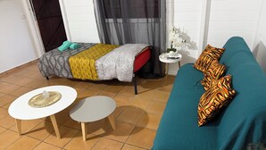 Een kamer met een bed, een bank, twee kleine tafels en een raam met gordijnen.