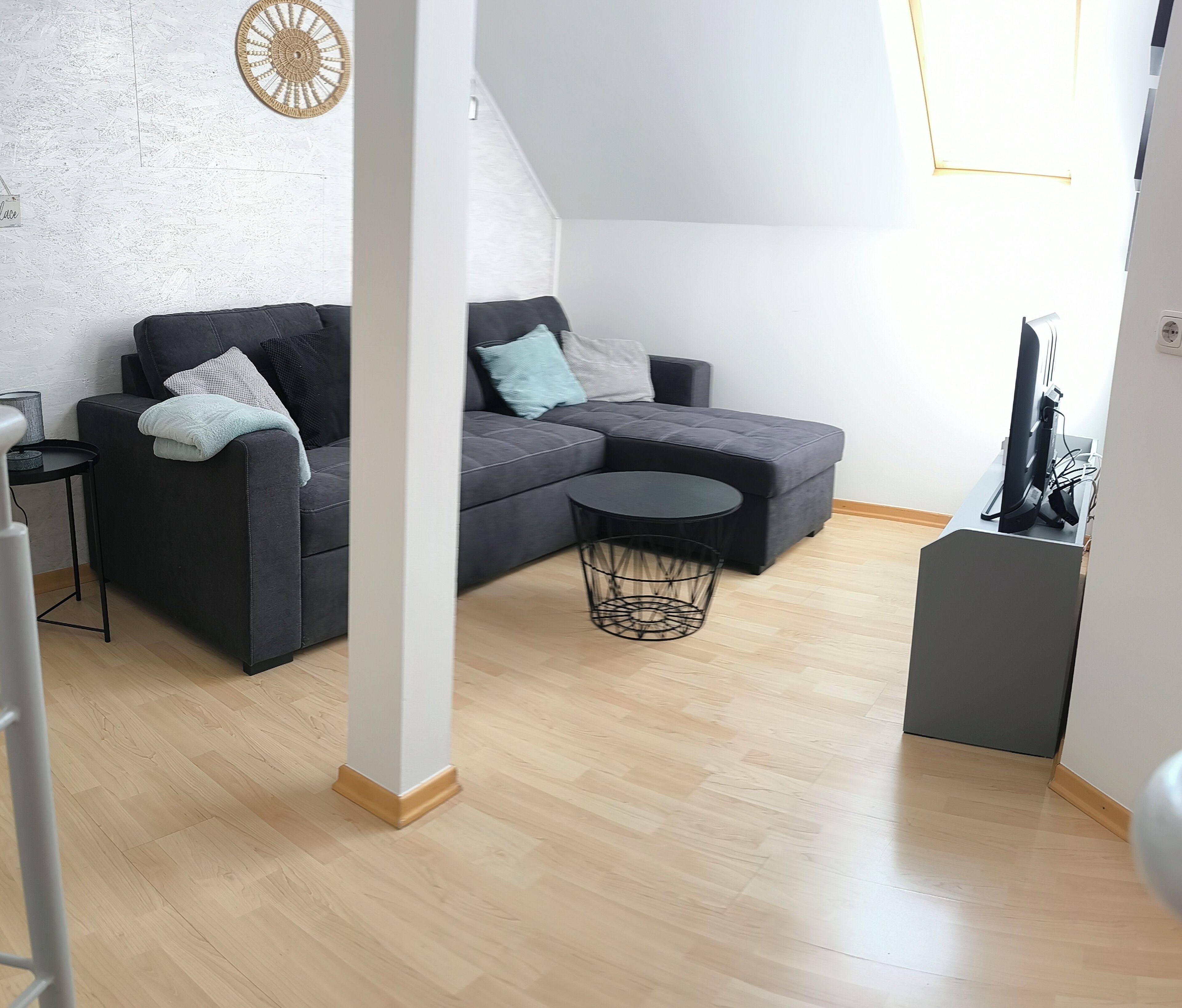 Una sala moderna con un sofá seccional gris, una mesa de centro redonda y una mesita auxiliar.