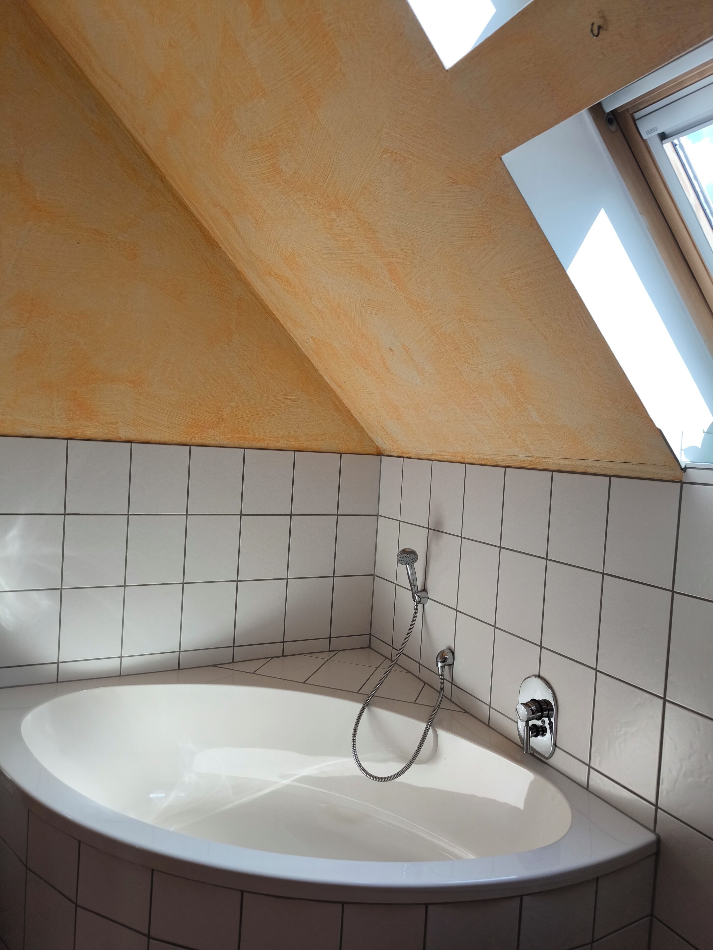 Un baño moderno con tragaluz, una bañera independiente y paredes con azulejos.