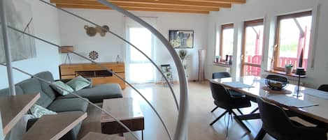 A modern interior with a wooden staircase, a dining area, and a living space with a sofa and a coffee table.