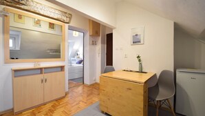 A compact kitchen with wooden cabinets, a wooden dining table, and a refrigerator. - RentPlanet - Apartament Narutowicza (Kołobrzeg)