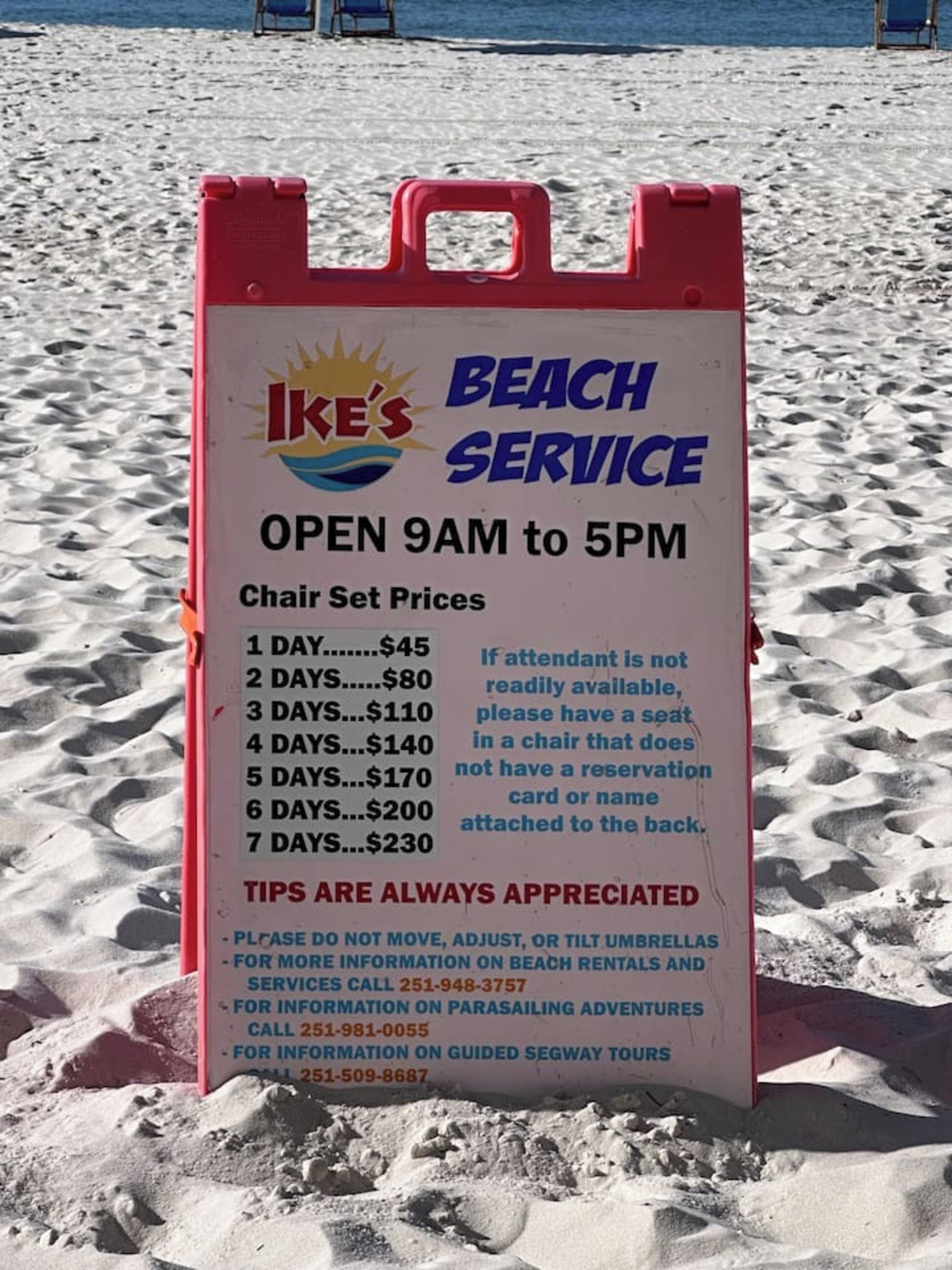 Schild mit Stranddienst-Preisen und Öffnungszeiten.