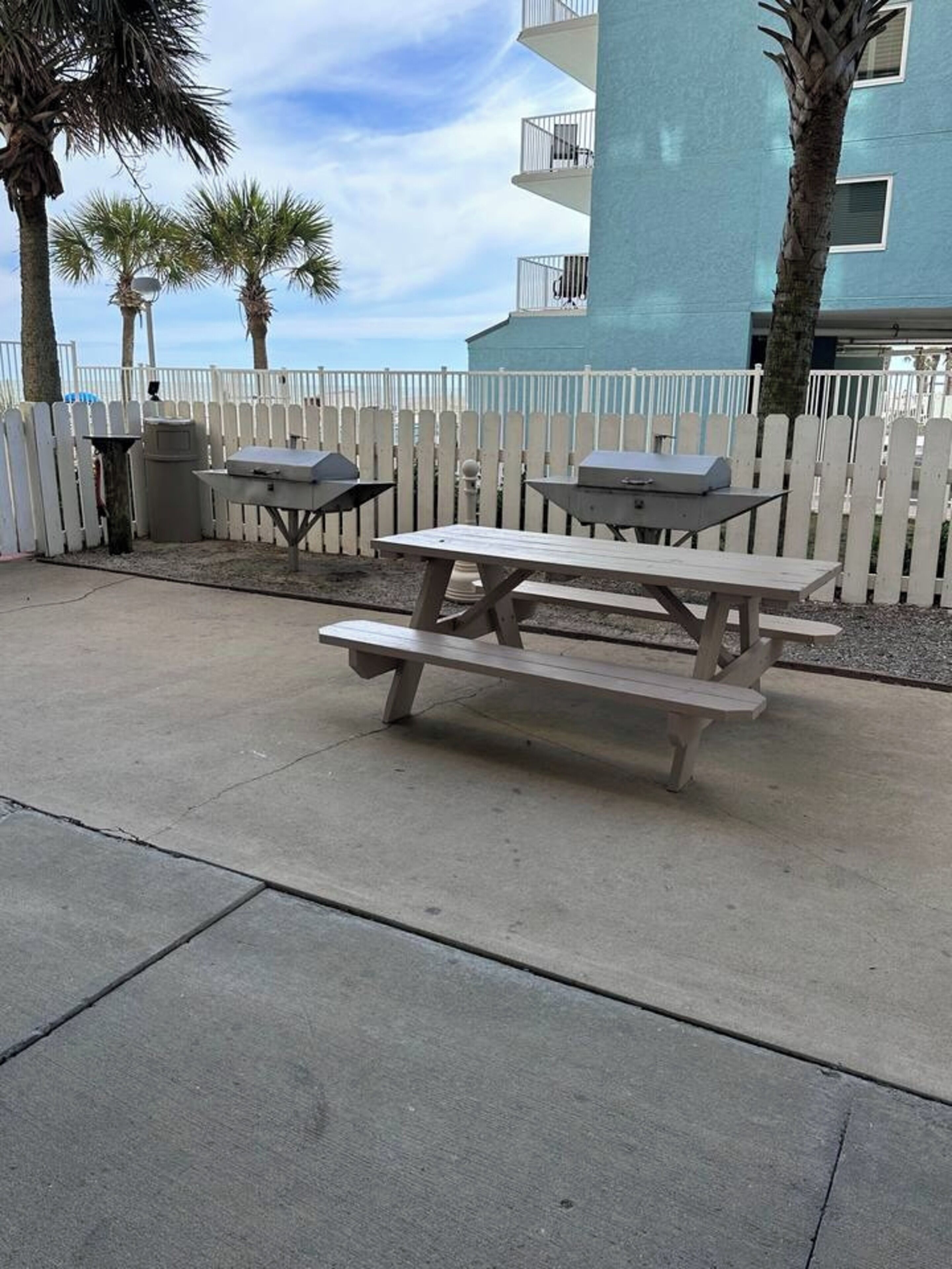 A concrete patio with a picnic table and two barbecue grills.