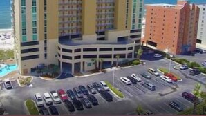 Un hotel de varios pisos con un patio central y aparcamiento.