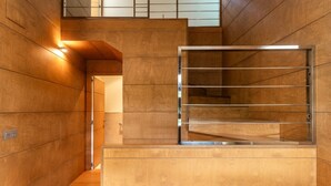 A modern interior with wooden panel walls, a metal-framed window, and a staircase. - VILLA WITH LAND IN LLANES (La Pereda)