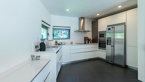 A modern kitchen with white cabinetry, a stainless steel refrigerator, an oven, and a microwave. - VILLA WITH LAND IN LLANES (La Pereda)