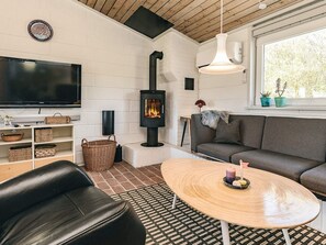 Ein gemütliches Wohnzimmer mit Kamin, einer Couch, einem Fernseher und einem Couchtisch.