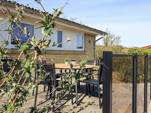 Ein Haus mit einer Terrasse, ausgestattet mit Tisch und Stühlen, umgeben von viel Grün.