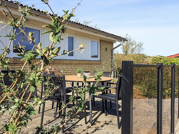 A house with a patio area featuring a table and chairs, surrounded by greenery. - 5 Person Holiday Home in Roslev (Roslev)