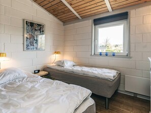 Een kamer met twee bedden, een raam met uitzicht, een schilderij aan de muur en een tafeltje met een lamp.